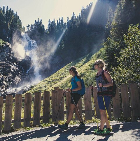 Zwei Wanderer beobachten einen Wasserfall