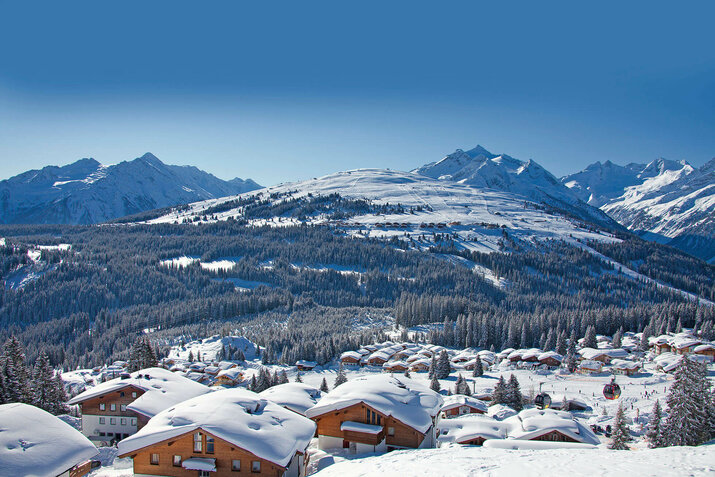 Blick auf ein schneebedecktes Dorf mit verschneiten Häusern und winterlichen Landschaften