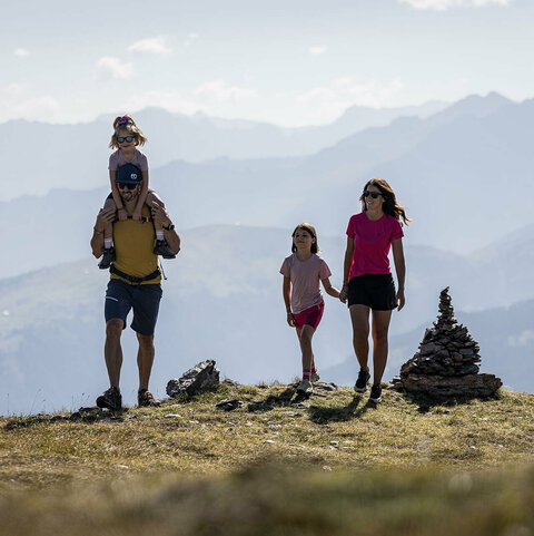 Ein Mann trägt ein kleines Mädchen auf seinen Schultern und eine Frau hält ein anderes Mädchen an der Hand