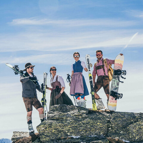 Zwei Männer und zwei Frauen in Trachtenkleidung und Skiausrüstung