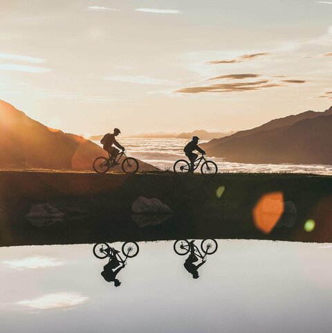 Zwei Radfahrer radeln bei Sonnenuntergang.