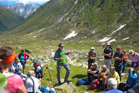 Ein Mann steht inmitten einer Wandergruppe und erklärt ihnen etwas