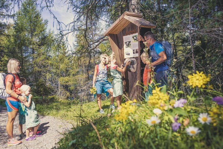 Eine Familie steht vor einer Infotafel.