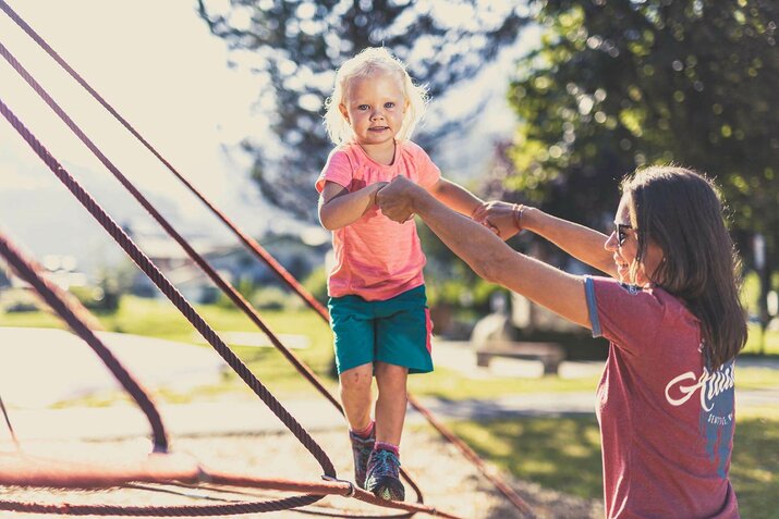 Eine Frau und ein kleines Mädchen spielen auf dem Spielplatz