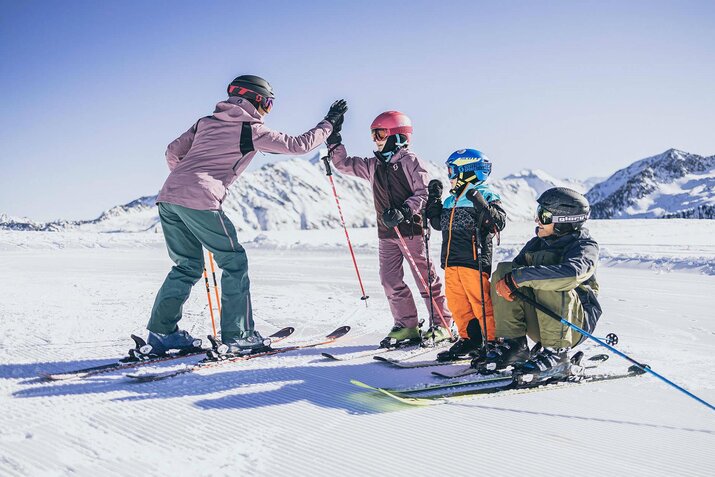 Eine Frau, ein Mann und zwei Kinder stehen auf der Piste auf ihren Skiern