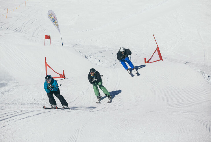 Drei Schifahrer rasen die Piste hinunter