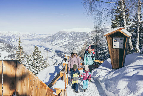 Zwei Frauen und drei Kinder spazieren durch den Schnee