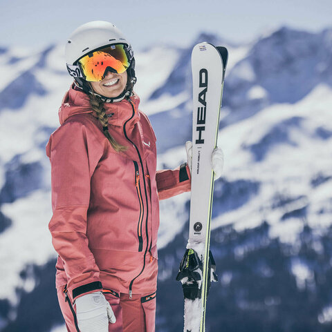 Eine Skifahrerin steht vor einer traumhaften Bergkulisse