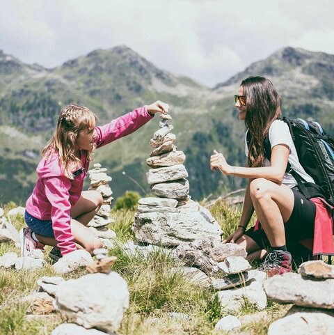 Eine Frau und ein Mädchen bauen einen Steinturm