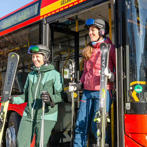 Skibus Skifahrer steigen aus einem roten Bus aus
