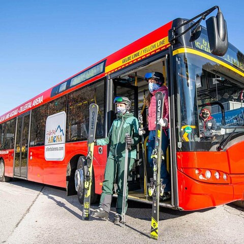 Skifahrer steigen aus einem roten Bus aus