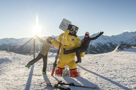 Ein Mann und eine Frau machen ein Foto mit dem gelben Maskottchen Funty