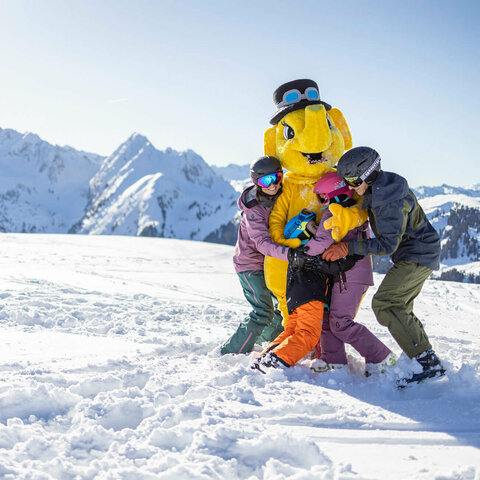 Family & Kids Eine Familie umarmt das Maskottchen Funty