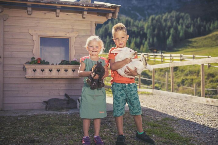 Zwei Kinder halten Kaninchen in der Hand.