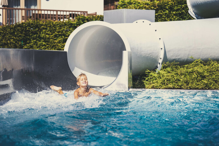 Ein kleiner Junge rutscht auf einer weißen Wasserrutsche