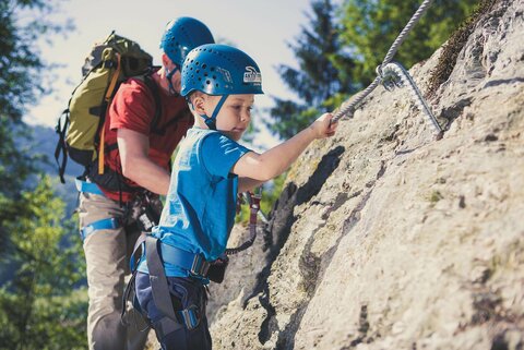 Ein Mann und ein kleiner Junge klettern im Klettersteig Talbach