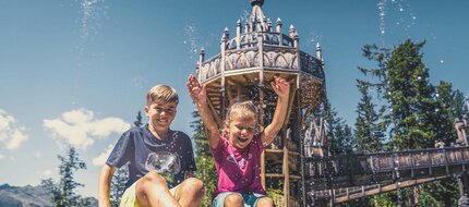 Ein Mädchen und ein Junge spielen an einem Wasserbecken.