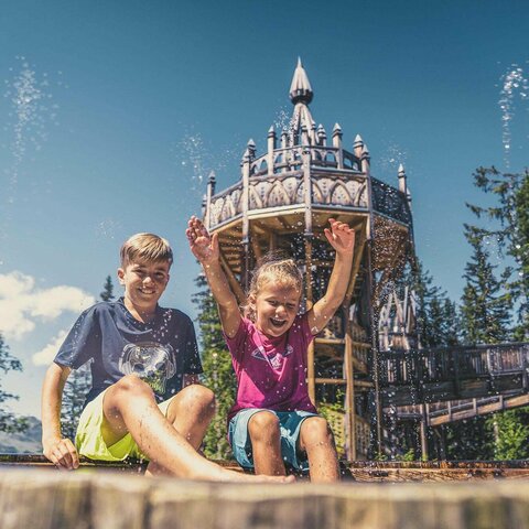 Ein Mädchen und ein Junge spielen an einem Wasserbecken.