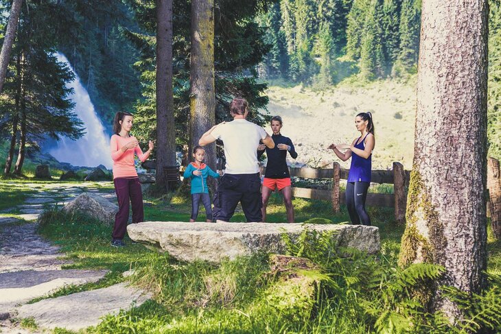 Ein Mann zeigt drei Frauen und einem Mädchen Entspannungstechniken
