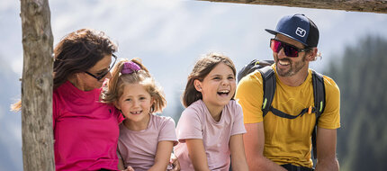 Eine Familie sitzt lachend in der Natur