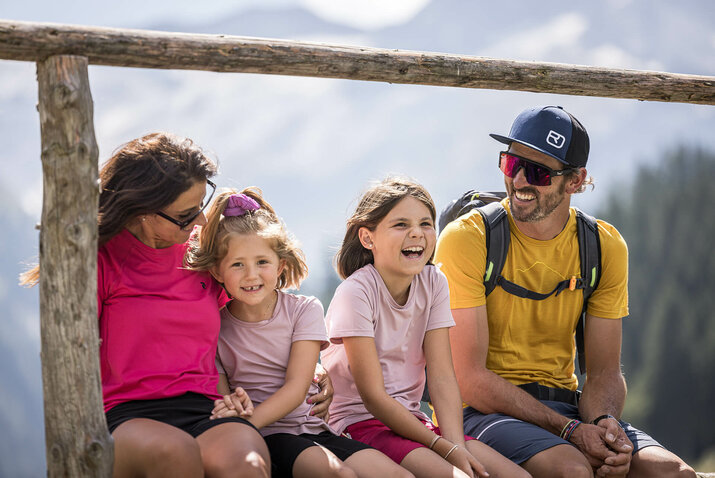 Eine Familie sitzt lachend in der Natur