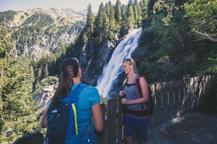 Zwei Frauen beobachten einen Wasserfall
