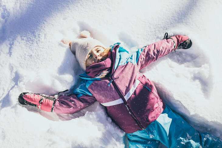 Ein kleines Mädchen liegt im Schnee