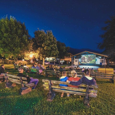 Zuschauer sitzen auf Holzbänken beim Fallkino Krimml