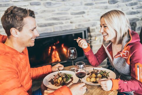 Ein Mann und eine Frau Essen und Trinken vor einem Kaminfeuer