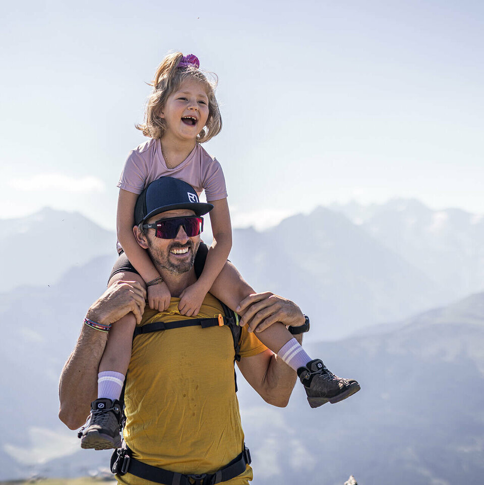 Ein Mann trägt ein kleines Mädchen auf seinen Schultern