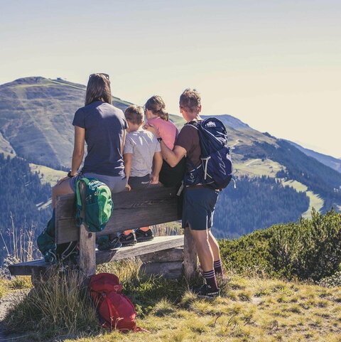 Eine Familie sitzt auf einer Bank und beobachtet eine traumhafte Bergkulisse