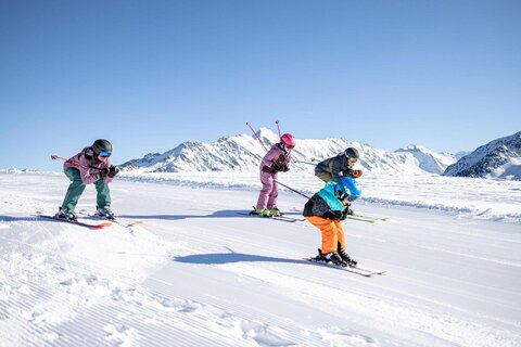 Eine Frau, ein Mann und zwei Kinder fahren die Piste hinunter