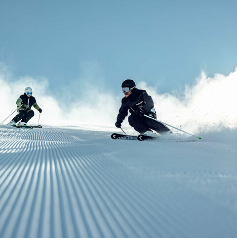 Zwei Schifahrer fahren die Piste herunter