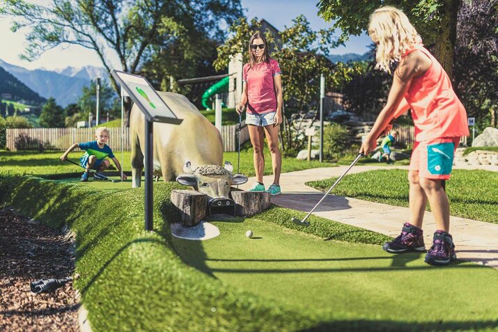 Eine Frau und zwei Kinder spielen Minigolf