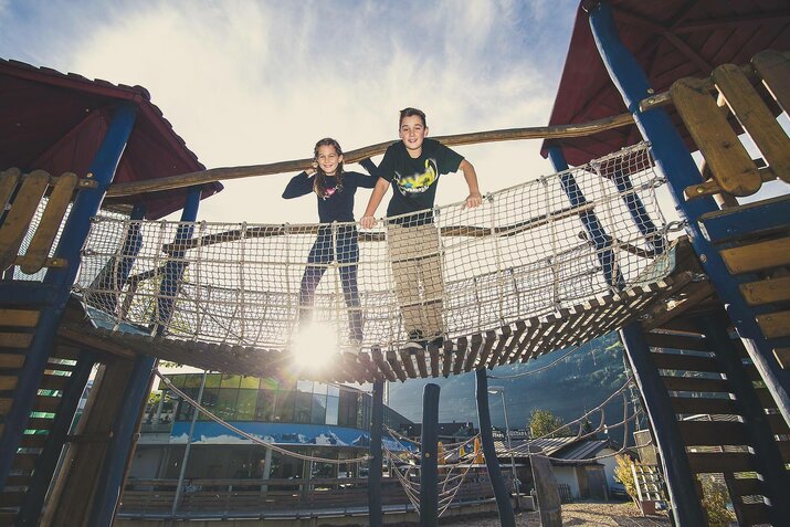 Ein Mädchen und ein Junge spielen auf einem Spielplatz.