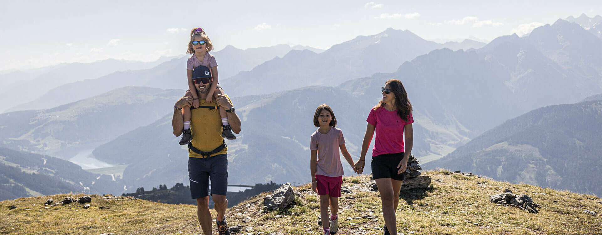 Ein Mann, eine Frau und zwei Mädchen wandern durch eine schöne Berglandschaft