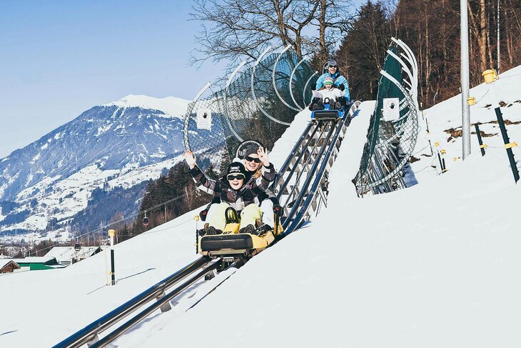Eine Familie fährt mit der Winterrodelbahn