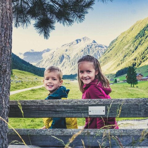 Ein Mädchen und ein Junge sitzen auf einer Holzbank