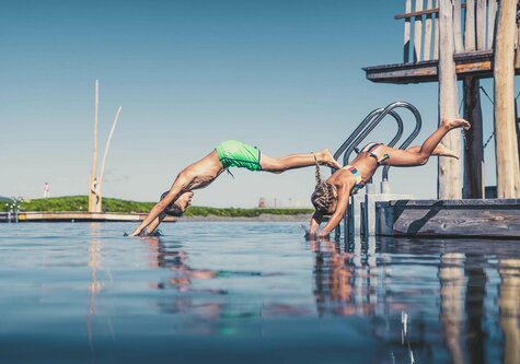 Ein Mädchen und ein Junge machen einen Kopfsprung ins Wasser.