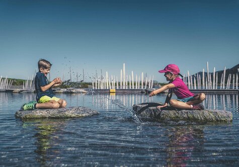 Ein Mädchen und ein Junge spielen im Wasser.