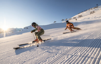 Zwei Skifahrer fahren eine Piste hinunter