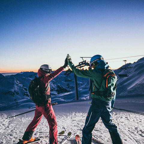 Zwei Skifahrer geben sich ein High-Five auf der Piste