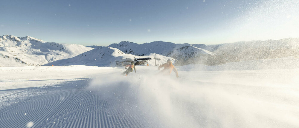 Zwei Skifahrer rasen die Piste hinunter