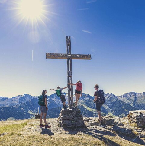 Arena-wandelpas Eine Familie steht bei einem Gipfelkreuz