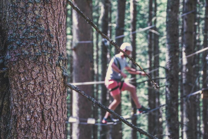 Mann im Hochseilgarten beim Sport Klettern