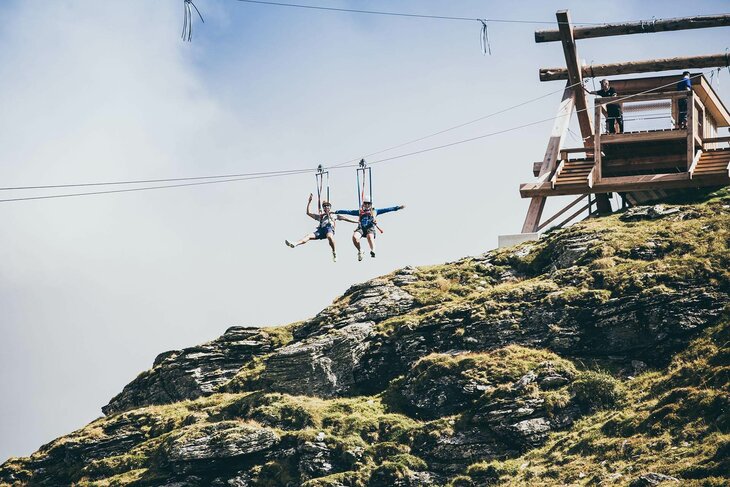 Zwei Personen fahren mit einer Zipline über der traumhaften Natur