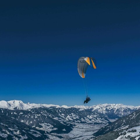 Ein Paragleiter zieht über die Gipfel der Berge