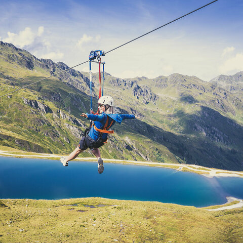 Eine Frau fährt mit einer Zipline über der traumhaften Natur