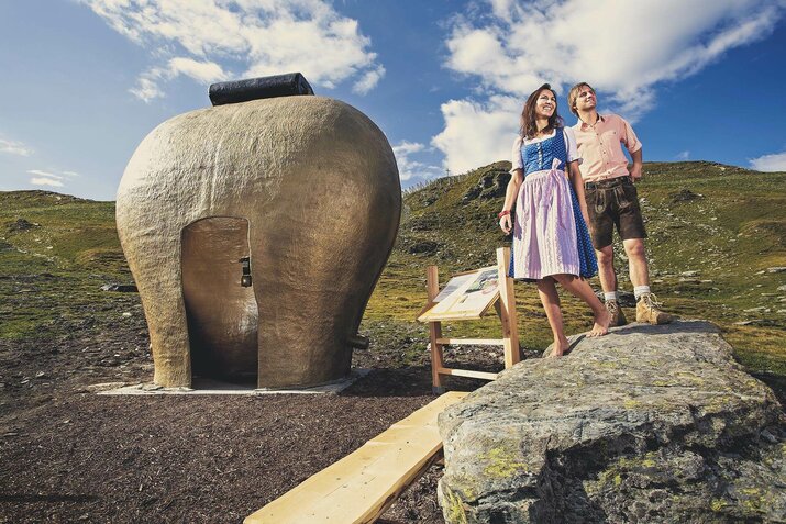 Ein Mann und eine Frau stehen vor einer großen Kuhglockenstatue