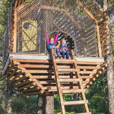 Zwei Mädchen sitzen in einem Baumhaus